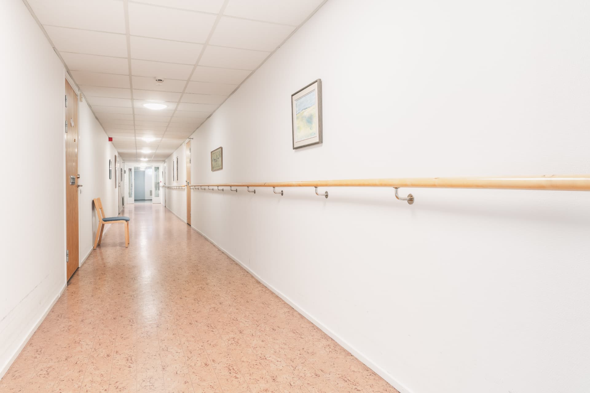 Ljus korridor med ledstång längs väggen och tavlor