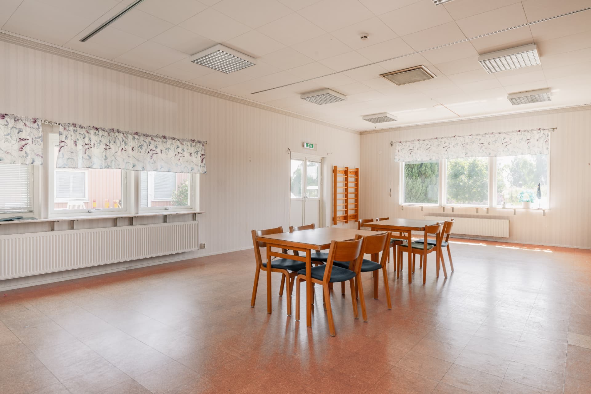 Mindre möteslokal med bord, stolar och stora fönster mot grönskan